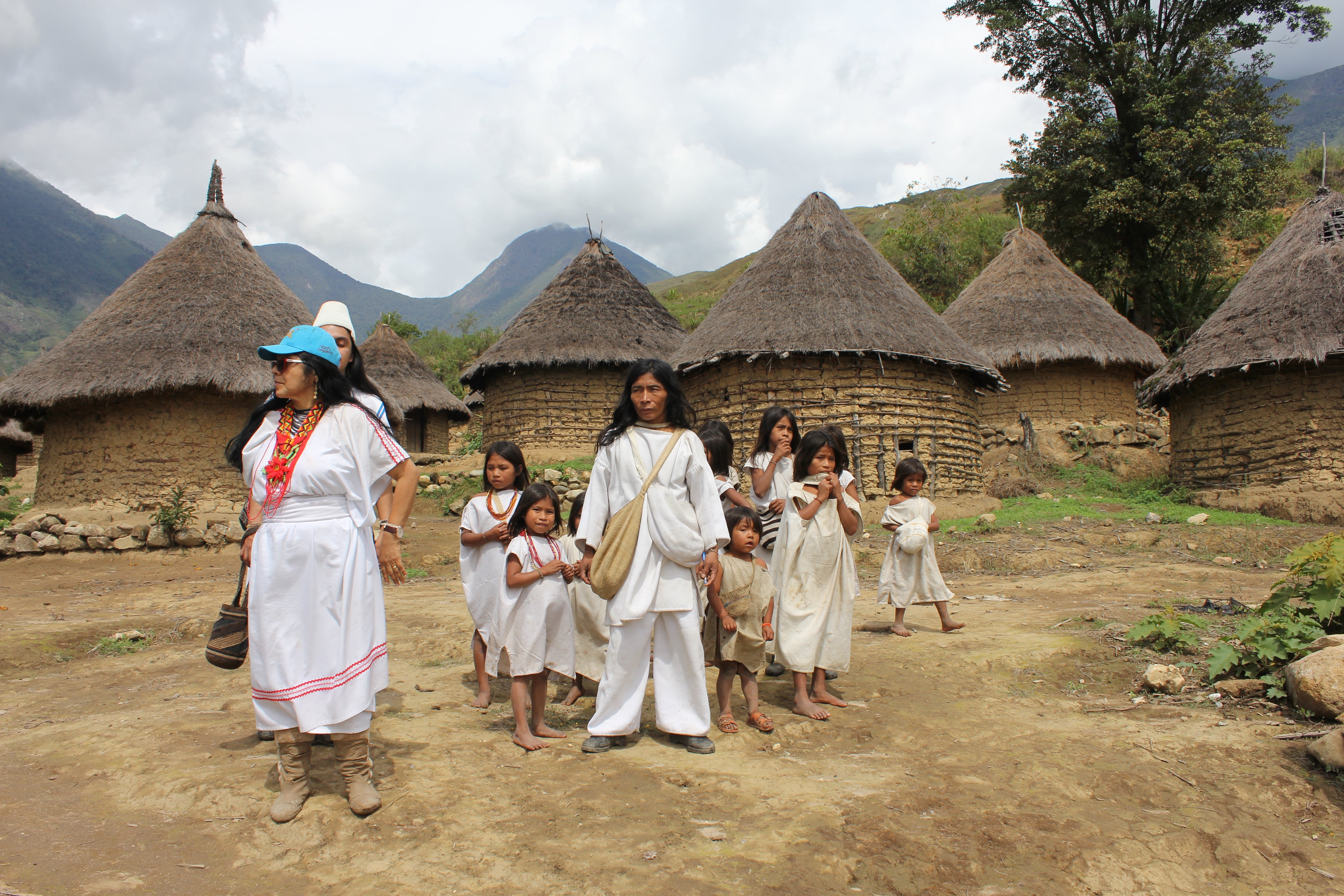 people in white in front of straw houses